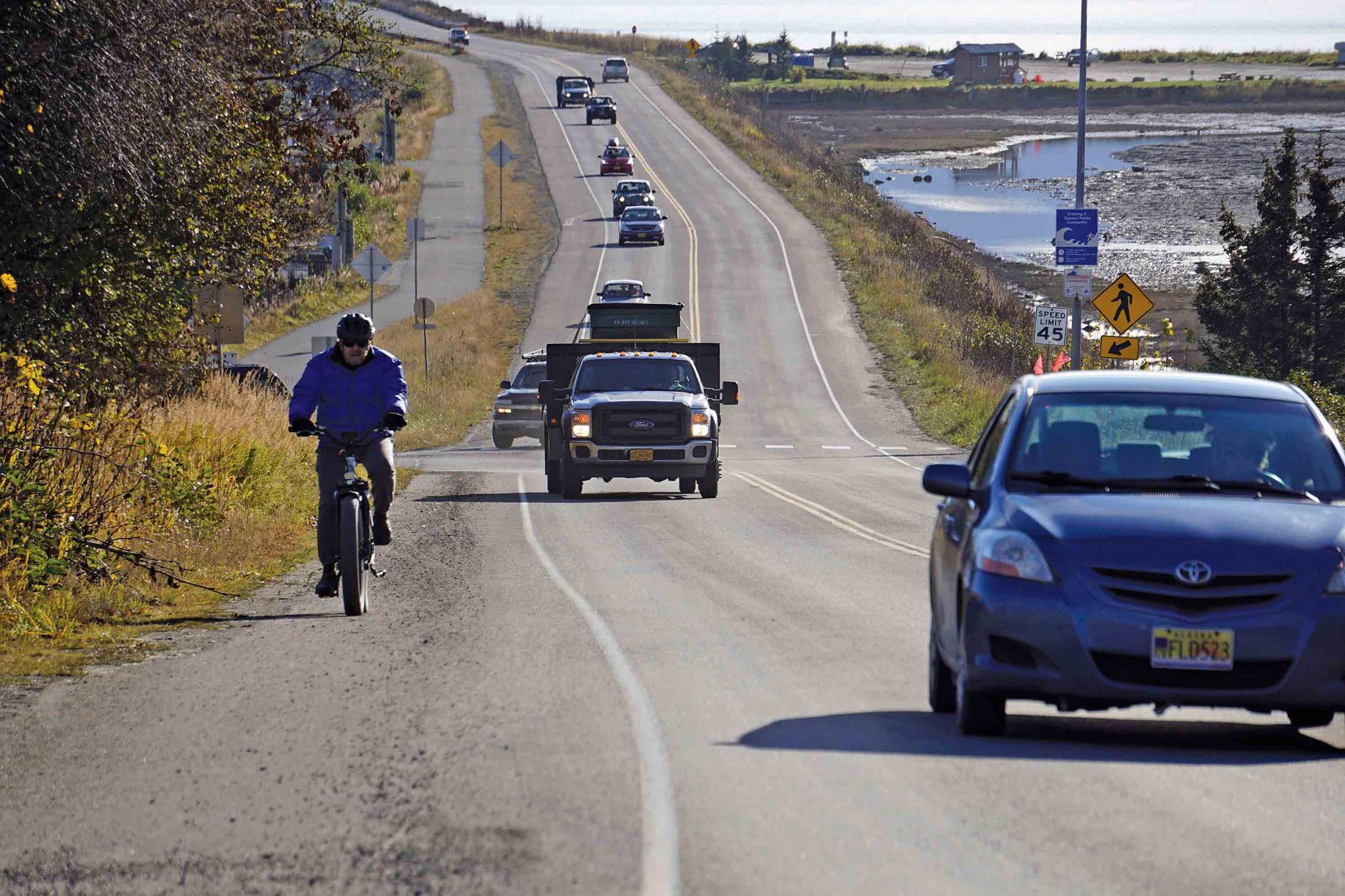 A biker leads a line of cars driving off the Homer Spit at about on Monday, Oct. 19, 2020, in Homer, Alaska after a tsunami evacuation order was issued for low-lying areas in Homer.