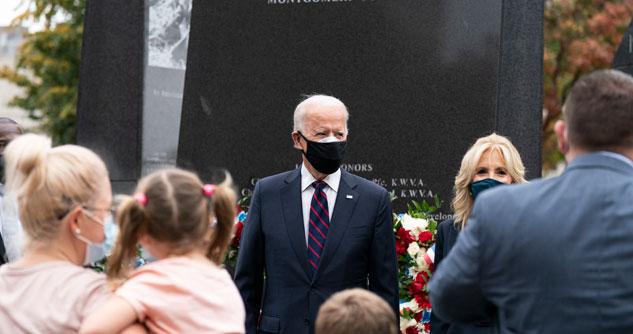 Joe and Jill Biden greet guests in front of a memorial 