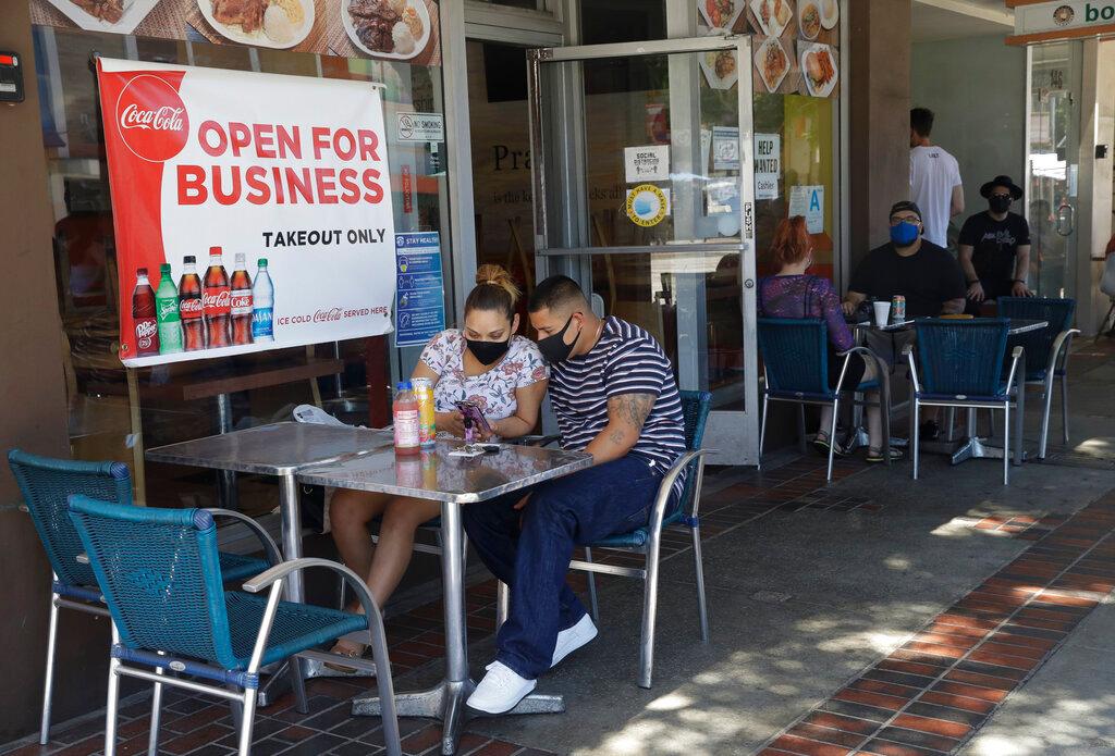 In this July 18, 2020, file photo, Josefina Pacheco, front left, and her husband Norberto wait to have a meal served outside at a restaurant in Burbank, Calif. Los Angeles County announced new coronavirus-related restrictions Sunday, Nov. 22, 2020, that will prohibit in-person dining for at least three weeks as cases rise at the start of the holiday season and officials statewide begged Californians to avoid traveling or gathering in groups for Thanksgiving. The new restrictions in Los Angeles County, the nation's most populous, came as the California Department of Health and Human Services reported more than 15,000 coronavirus cases statewide Saturday, by far the highest level since the pandemic began in March. Another 14,000 cases were recorded Sunday. 