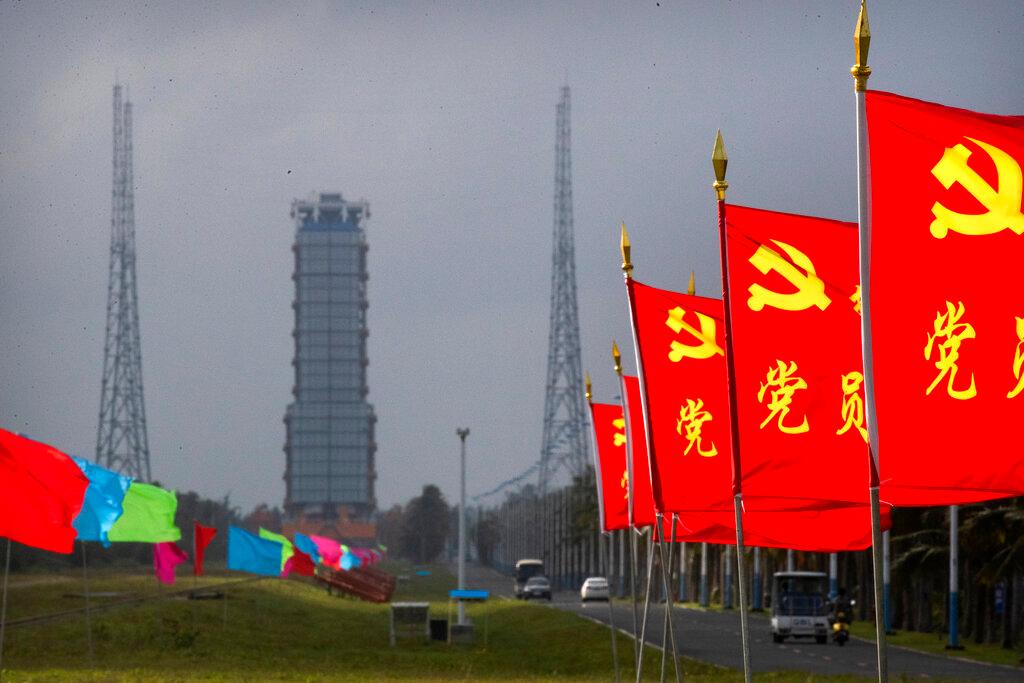 Flags with the logo of the Communist Party of China fly in the breeze near a launch pad at the Wenchang Space Launch Site i