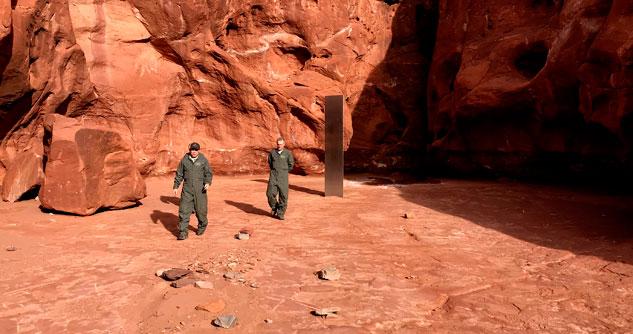 Utah state workers walk near a metal monolith