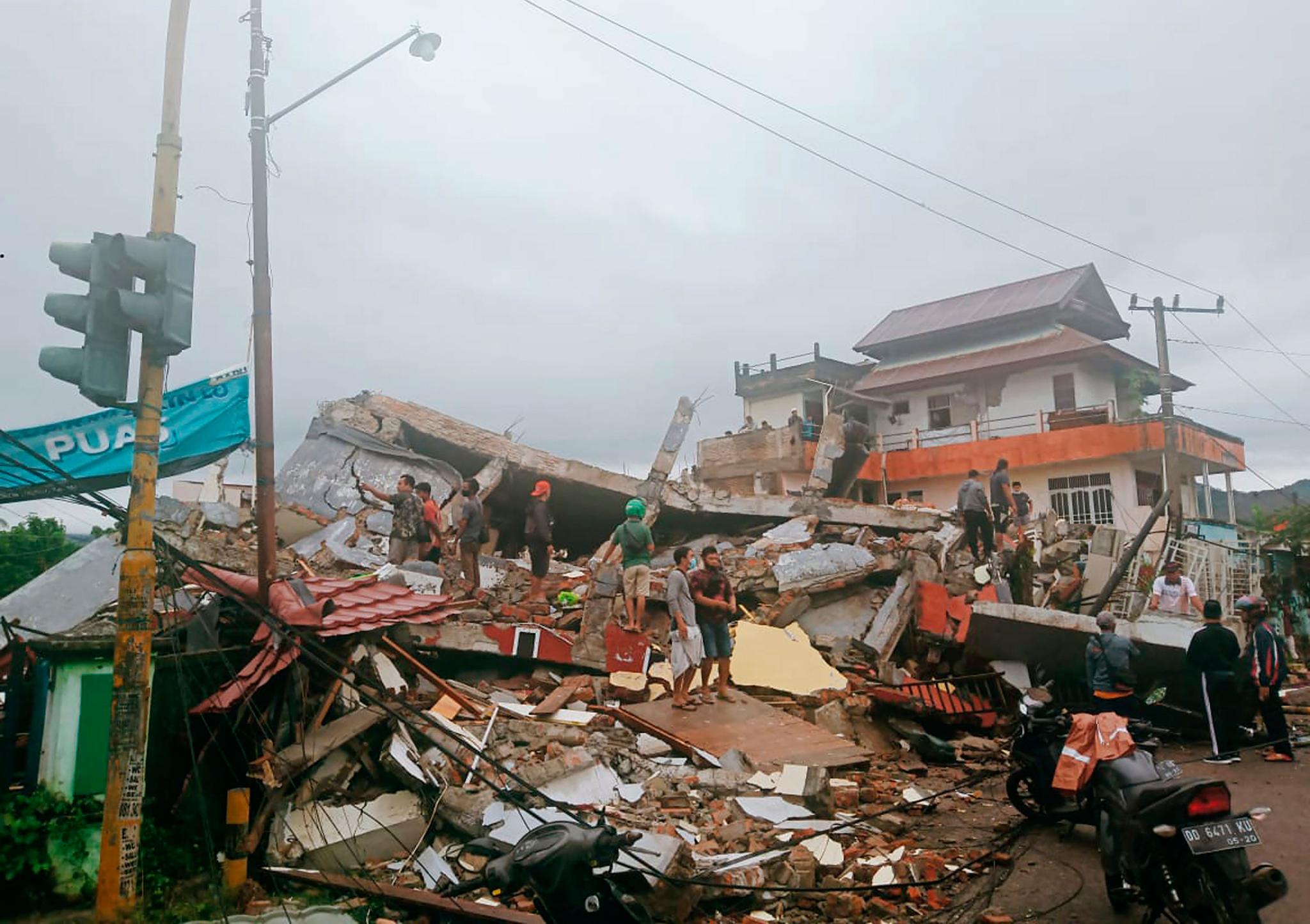 Residents inspect earthquake-damaged buildings in Mamuju, West Sulawesi, Indonesia