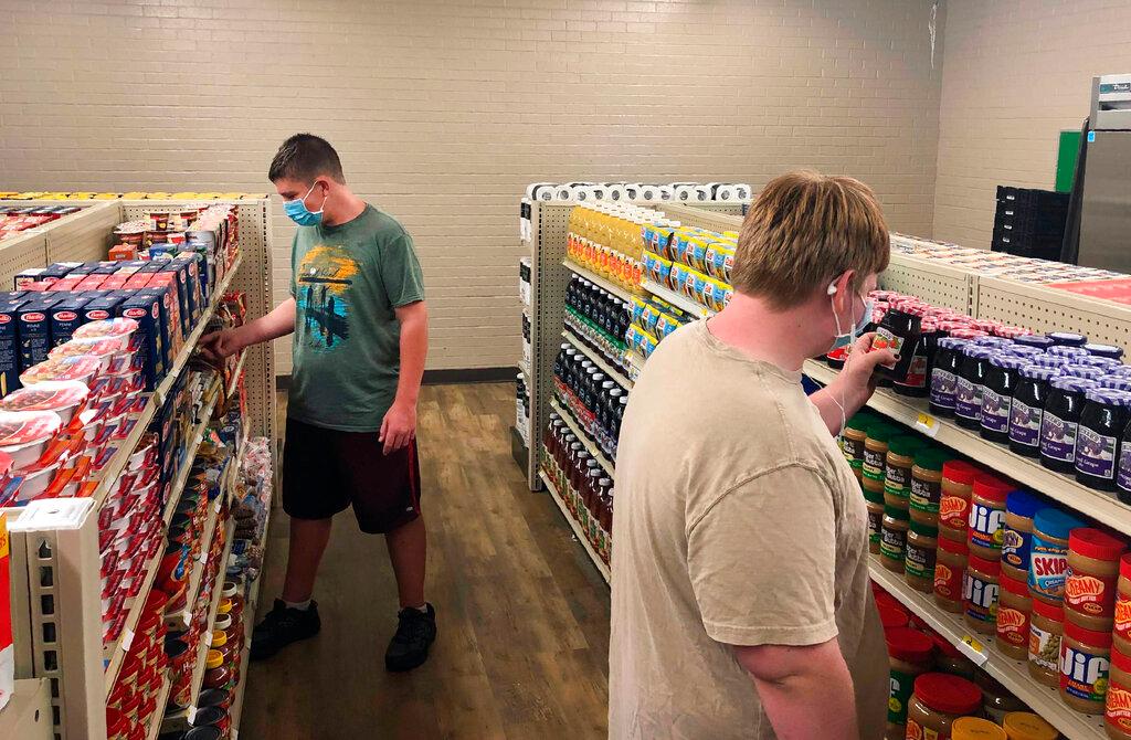 Hunter Weertman, 16, left, stocks shelves and takes inventory while working as a manager of the student-led free grocery store at Linda Tutt High School