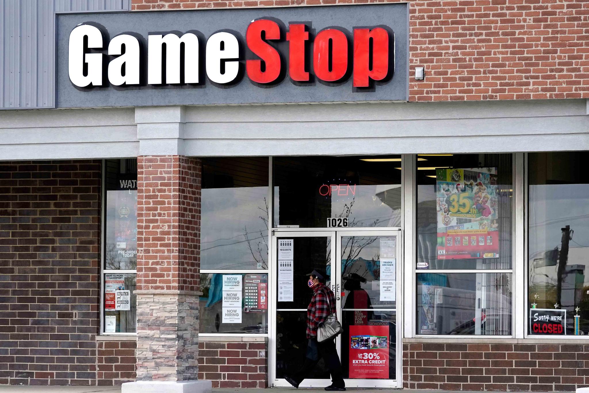 A woman wears a face mask as she walks past a GameStop store in Des Plaines, Ill., Thursday, Oct. 15, 2020.