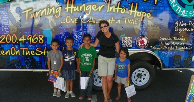 Four small children in front of a painted truck with a woman smiling