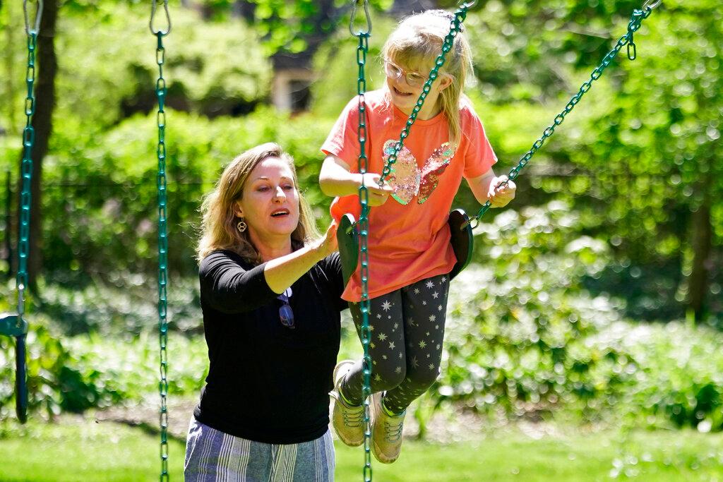 Holly Christensen, left, pushes her daughter, Lyra, on a swing in Akron, Ohio