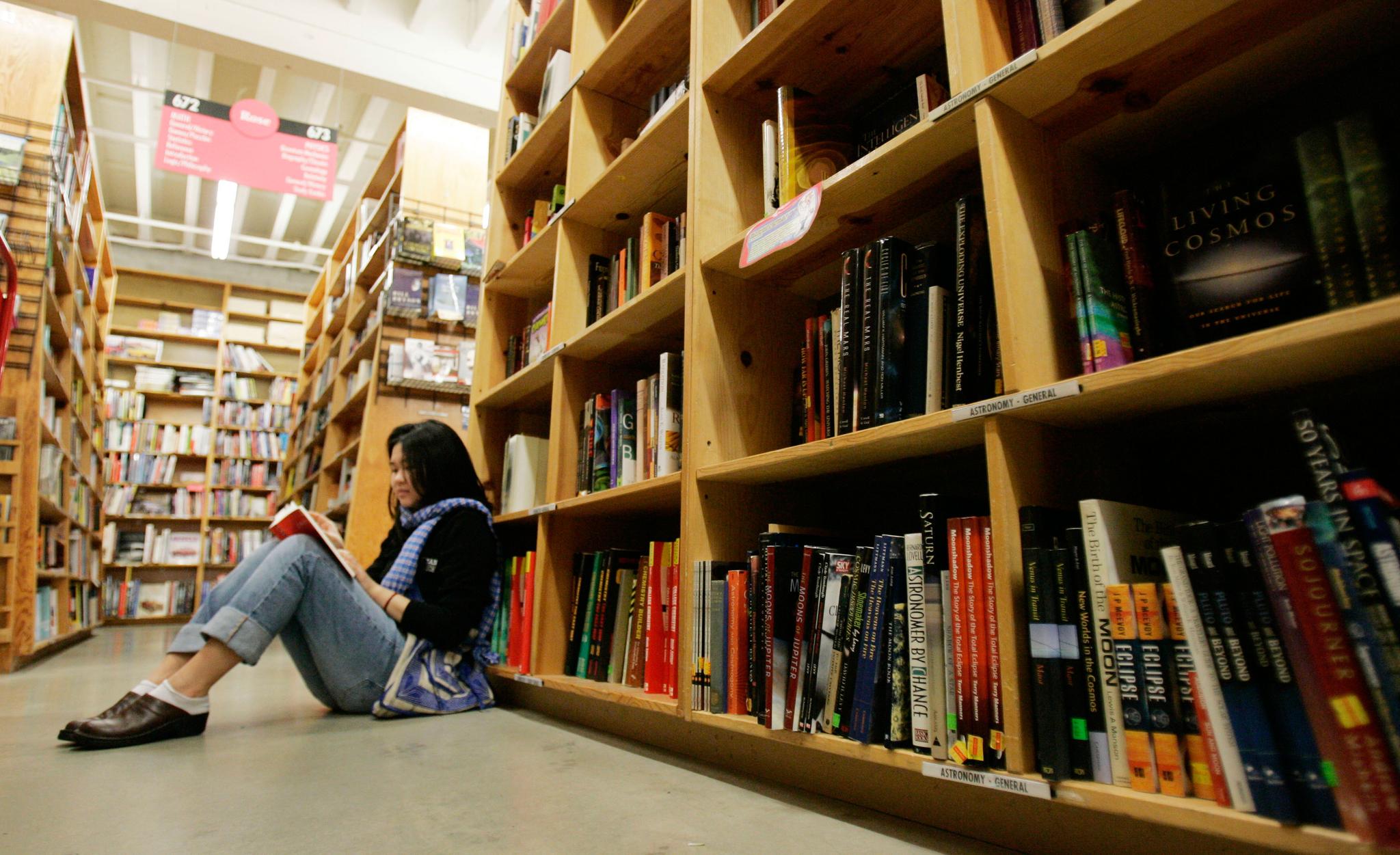 woman sits near book shelves