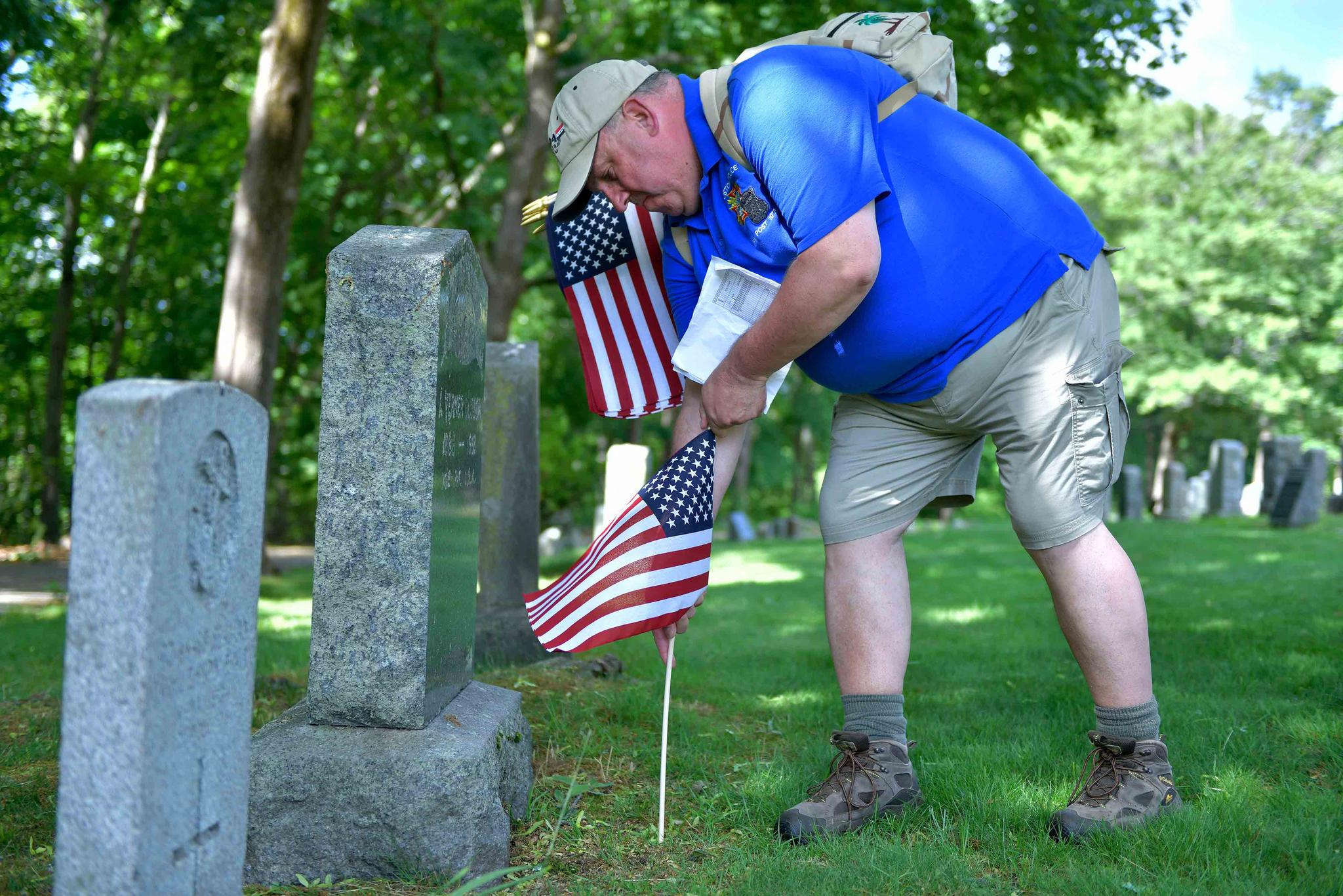 Craig DeOld, a retired Army Captain, and commander of the Boston Police VFW, replaces flags at veteran's graves Thursday, May 27, 2021, in the Fairview Cemetery in Boston.