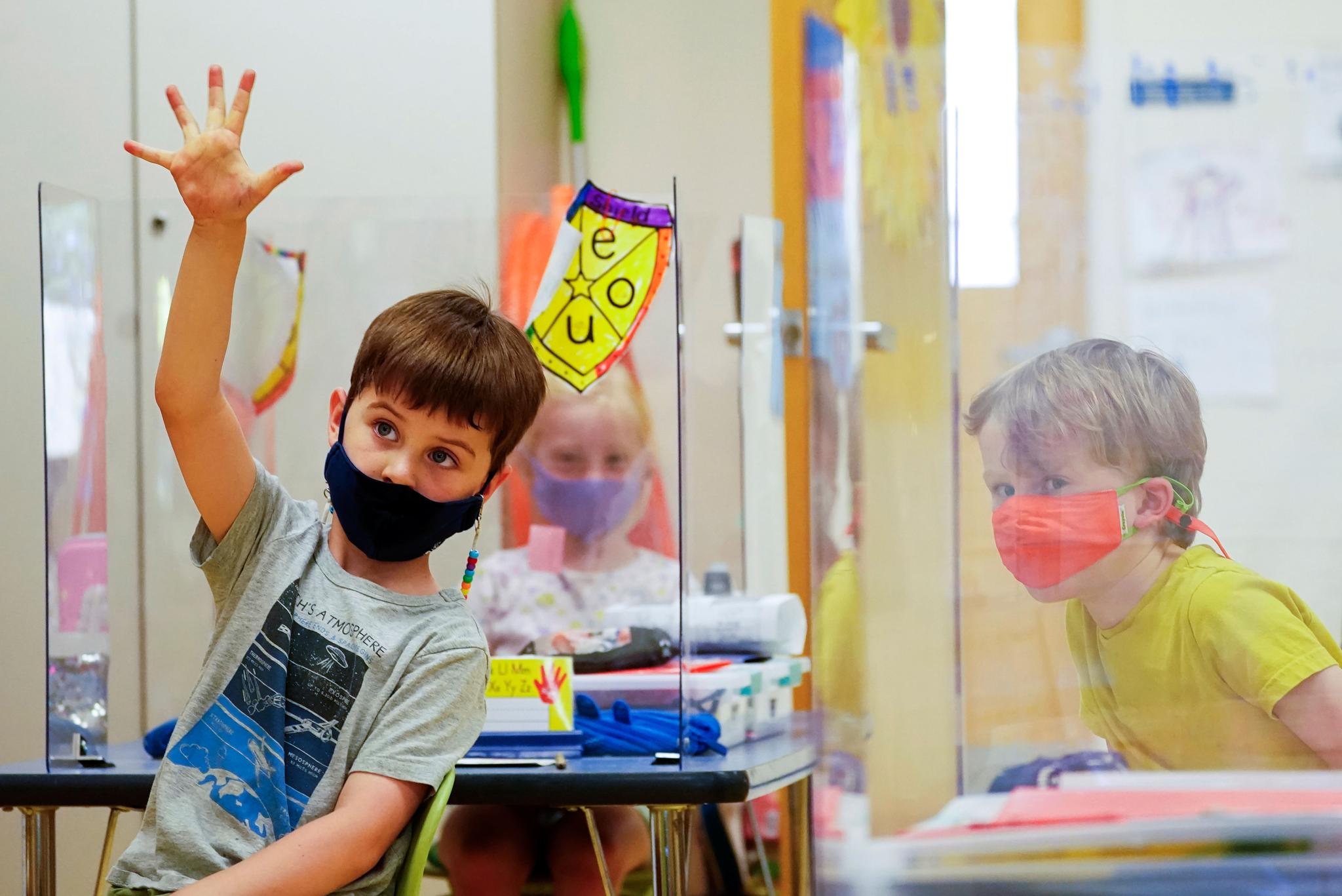 kindergarten students wear masks and are separated by plexiglass