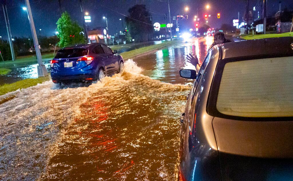 Lamont Pepp, right, waves to a passing motorist to slow down after Pepp's car stalled in high water on Gause Boulevard in Slidell late Friday, June 18, 2021, as a tropical disturbance neared the Louisiana shore. Tropical Storm Claudette has formed Saturday morning along the U.S. Gulf Coast, bringing heavy rains and flooding to coastal states including Louisiana, Mississippi and Alabama.
