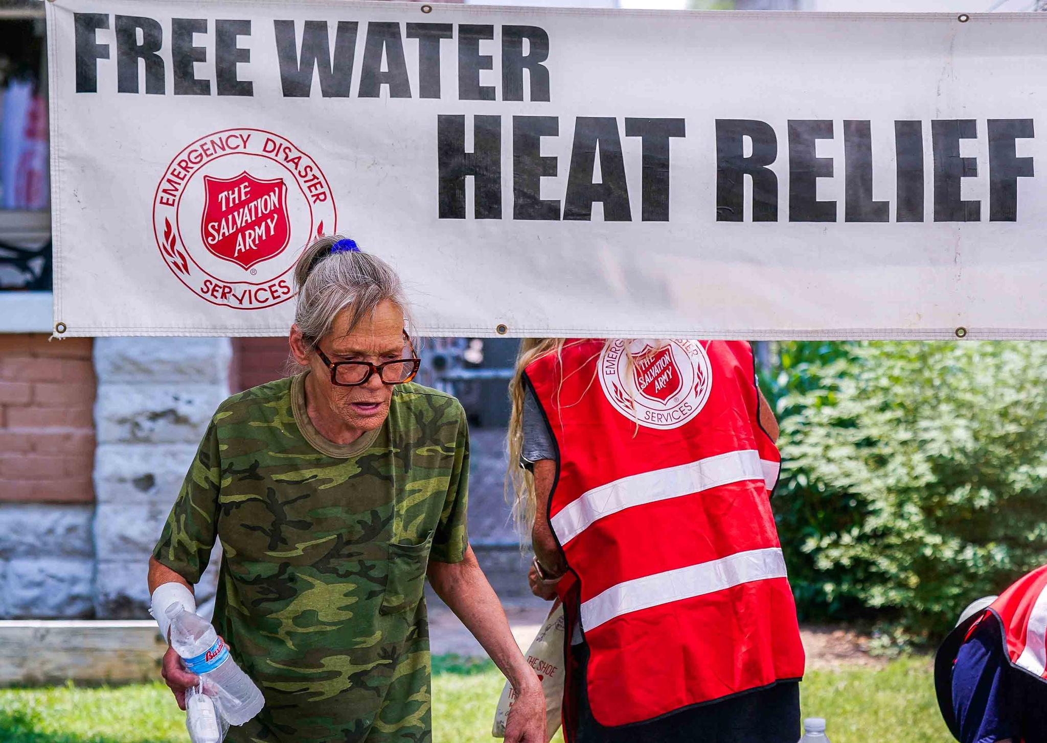 file photo, a pedestrian holds a bottle of cold water at a Salvation Army hydration station during a heatwave as temperatures hit 115-degrees in Phoenix.