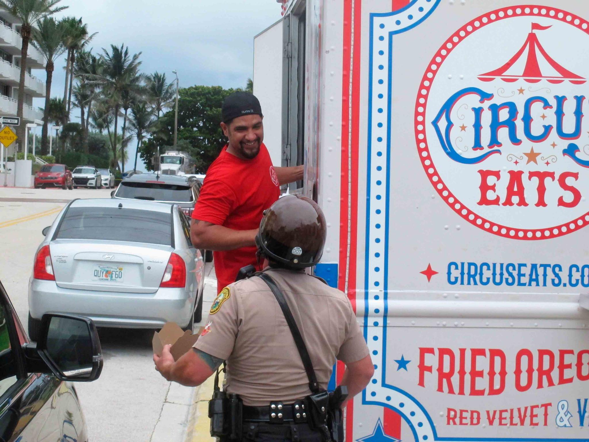 Robert Martinez talks with a law enforcement officer after handing him a hot meal from his food truck in Surfside, Fla.