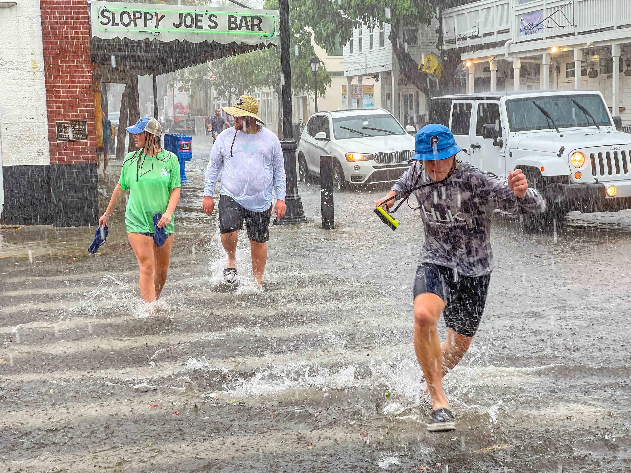 Pedestrians dash across the intersection of Greene and Duval streets as heavy winds and rain associated with Tropical Storm Elsa passes Key West, Fla.