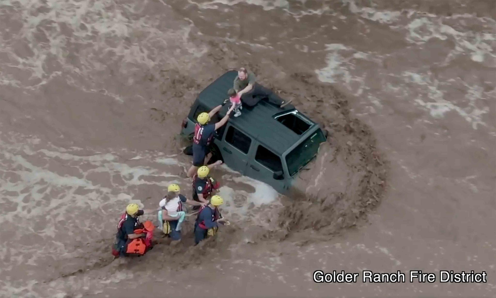 This drone image provided by the Golder Ranch Fire District shows firefighters safely rescue a man and his two daughters from the roof of their vehicle after it was swept away in fast moving water just north of Tucson, Ariz., on Wednesday, July 14, 2021. 
