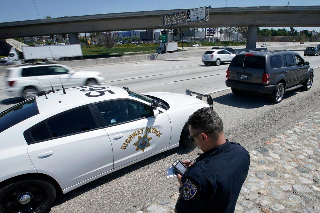 California Highway Patrol officer Troy Christensen runs a driver's license after stopping a motorist along Interstate 5 