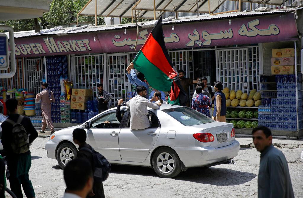 Afghans wave a black, red and green banner in honor of the Afghan flag — a banner that is becoming a symbol of defiance since the Taliban have their own flag