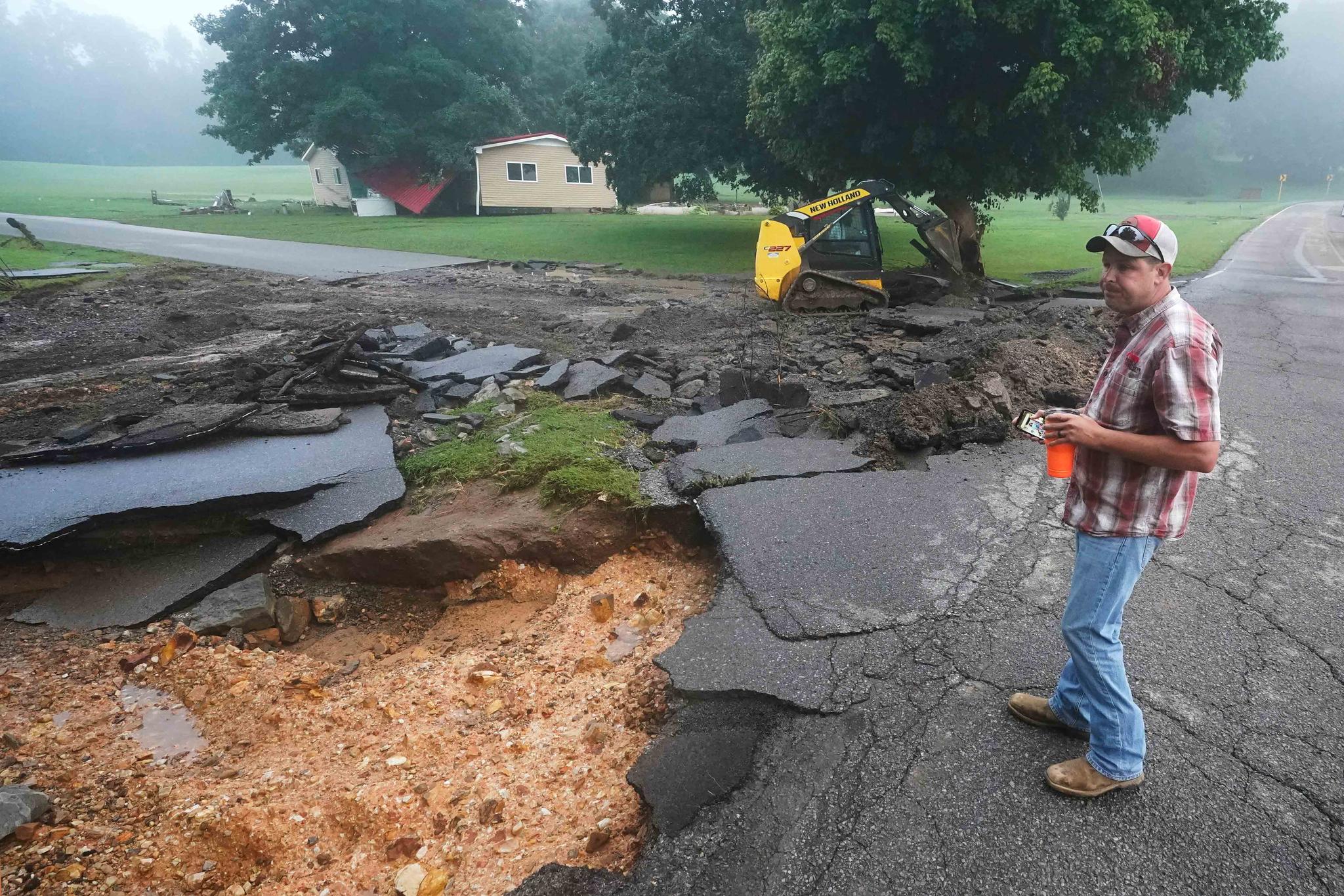 Michael Pate watches as a road is repaired Sunday, Aug. 22, 2021, in McEwen, Tenn. Pate repaired the road Saturday after heavy rain washed part of it away, but the road was damaged again when more rain fell Saturday night.