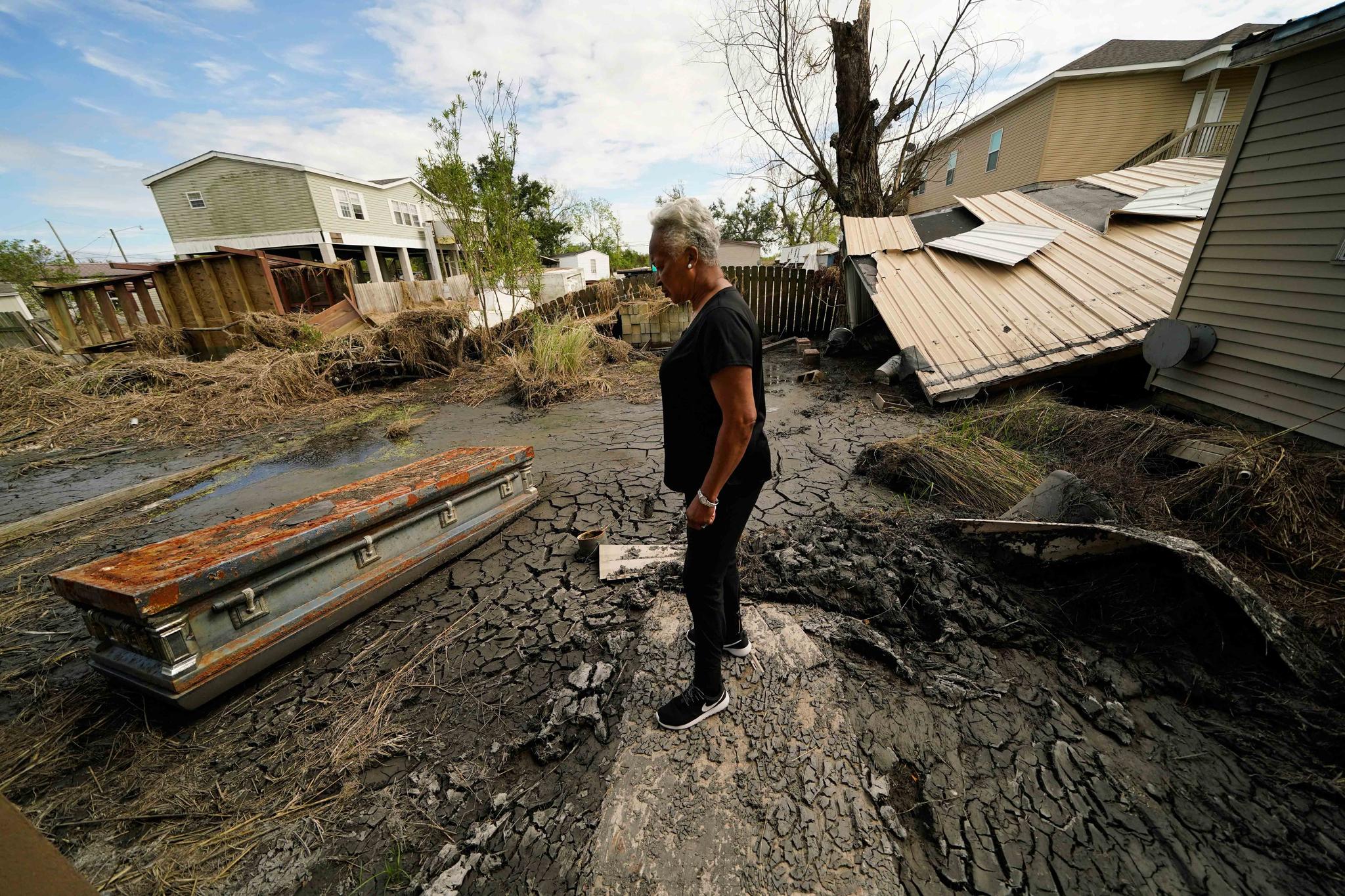 Audrey Trufant Salvant stands near a casket that floated in floodwaters from a nearby cemetery to her home in Ironton, La., Monday, Sept. 27, 2021