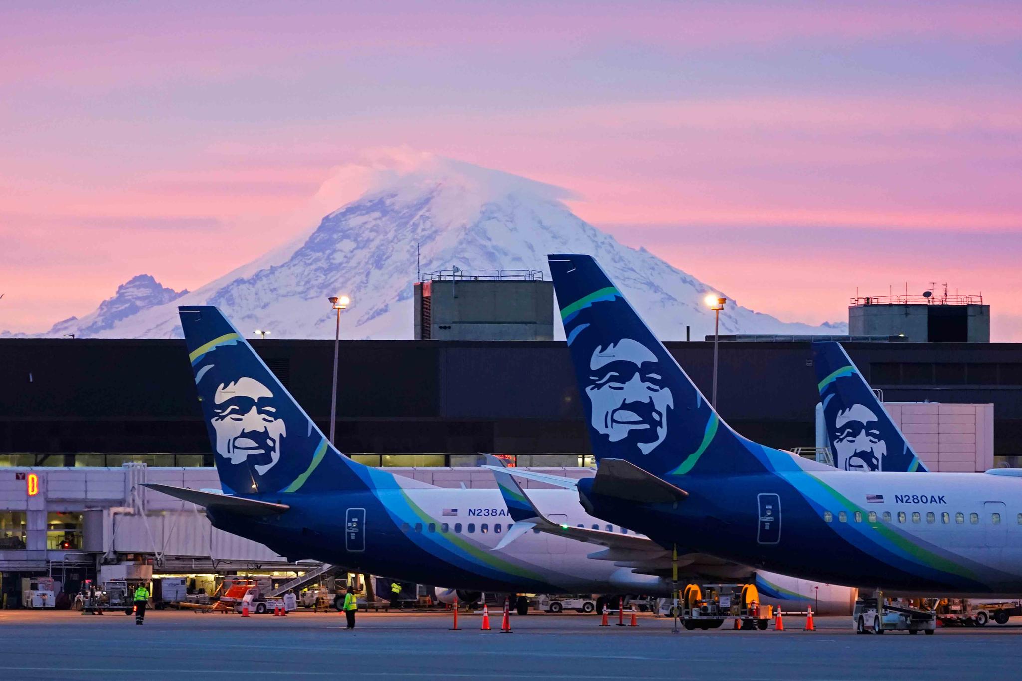 In this March 1, 2021 file photo Alaska Airlines planes are shown parked at gates with Mount Rainier in the background at sunrise, at Seattle-Tacoma International Airport in Seattle.