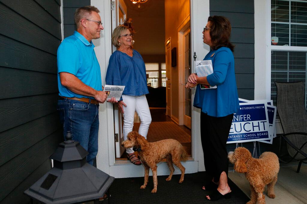 Jennifer Feucht, right, candidate for Olentangy Local Board of Education, delivers campaign flyers and yard signs to Brad, left, and Tina Krider Thursday, Oct. 7, 2021, in Westerville, Ohio. Across Ohio and the nation, parental protests over social issues like mask mandates, gender-neutral bathrooms, teachings on racial history, sexuality and mental and emotional health are being leveraged into school board takeover campaigns.