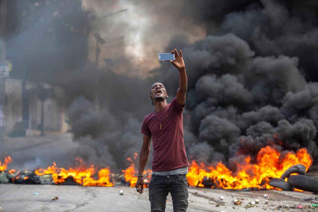 A protester takes a selfie at a burning barricade set by protesters in Port-au-Prince, Haiti, Monday, Oct. 18, 2021. Workers angry about the nation’s lack of security went on strike in protest two days after 17 members of a U.S.-based missionary group were abducted by a violent gang
