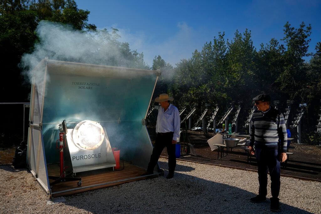 Antonio Durbe, left, and Daniele Tummei overlook the functioning of the "Purosole", Pure Sun, solar light coffee roaster, in Rome, Wednesday, Oct. 13, 2021. Two two electrical engineers, Antonio Durbe and Daniele Tummei, invented a plant that just needs a piece of land about the size of half a tennis court and sunny wether to toast up to 50kg of coffee an hour. No gas, no electricity, just sun rays concentrated by a set of mirrors on a rotating steel basket filled of fresh coffee grains.