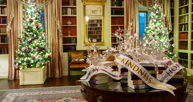 Two Christmas trees in a library-type room and a table draped with ribbons that say kindness, hope and joy