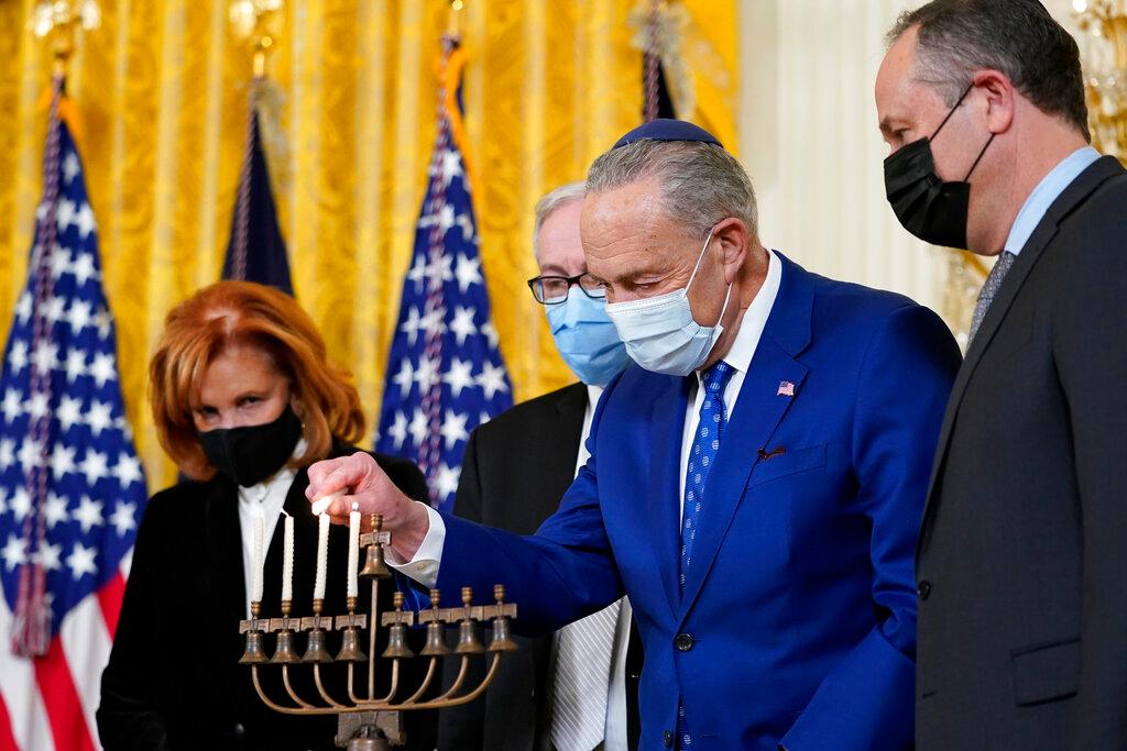 Senate Majority Leader Chuck Schumer of N.Y., second from right, lights the menorah in the East Room of the White House