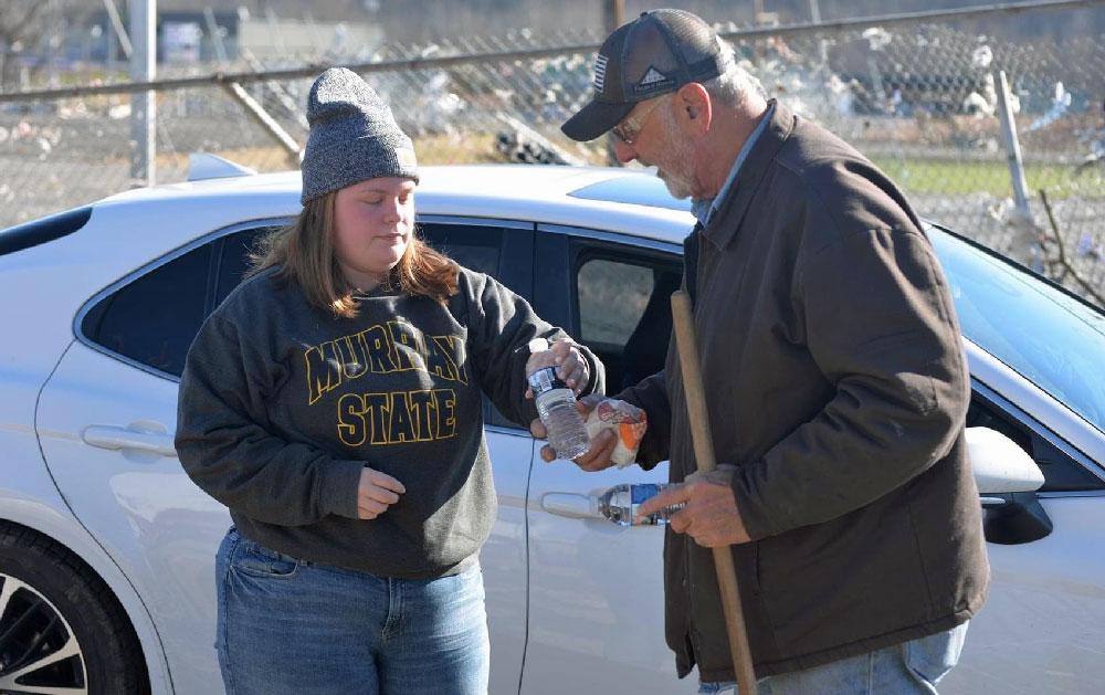 Whitney Shaw handing out safe water and breakfast biscuits 