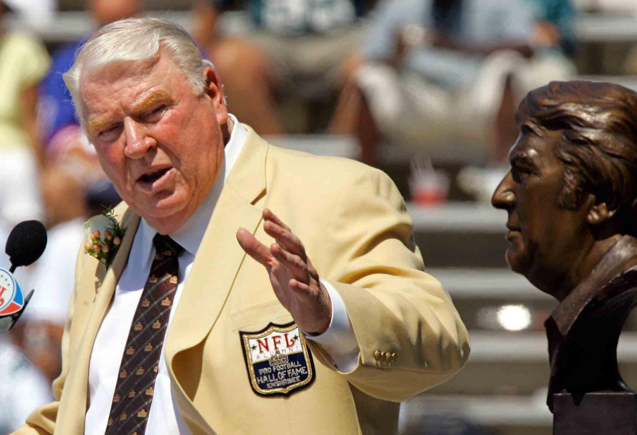 Former Oakland Raiders coach John Madden gestures toward a bust of himself during his enshrinement into the Pro Football Hall of Fame in Canton, Ohio, Aug. 5, 2006.