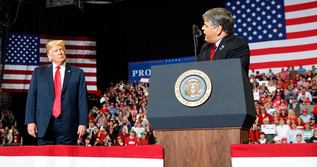 Pres. Trump and Sean Hannity on stage with American Flags in the background