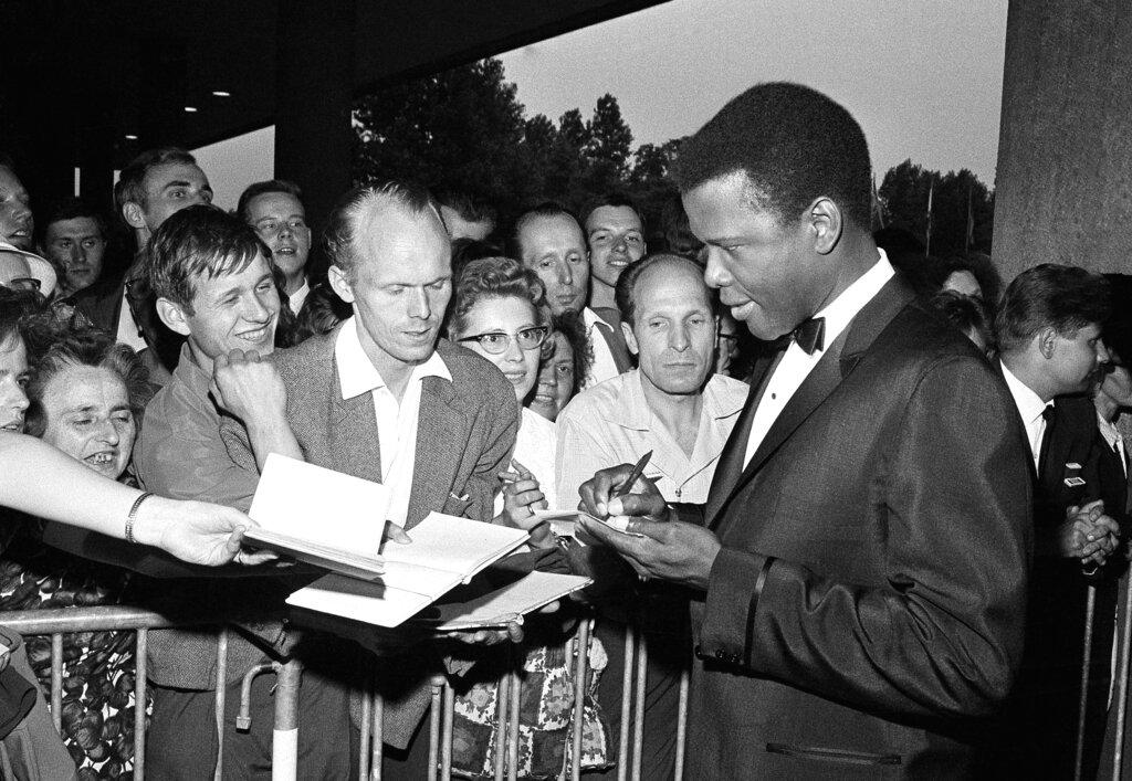 Sidney Poitier signs autographs before the opening of the 14th International Film Festival at the West Berlin congress hall on June 26, 1964 in Berlin. Poitier, the groundbreaking actor and enduring inspiration who transformed how Black people were portrayed on screen, became the first Black actor to win an Academy Award for best lead performance and the first to be a top box-office draw, died Thursday, Jan. 6, 2022 in the Bahamas. He was 94.