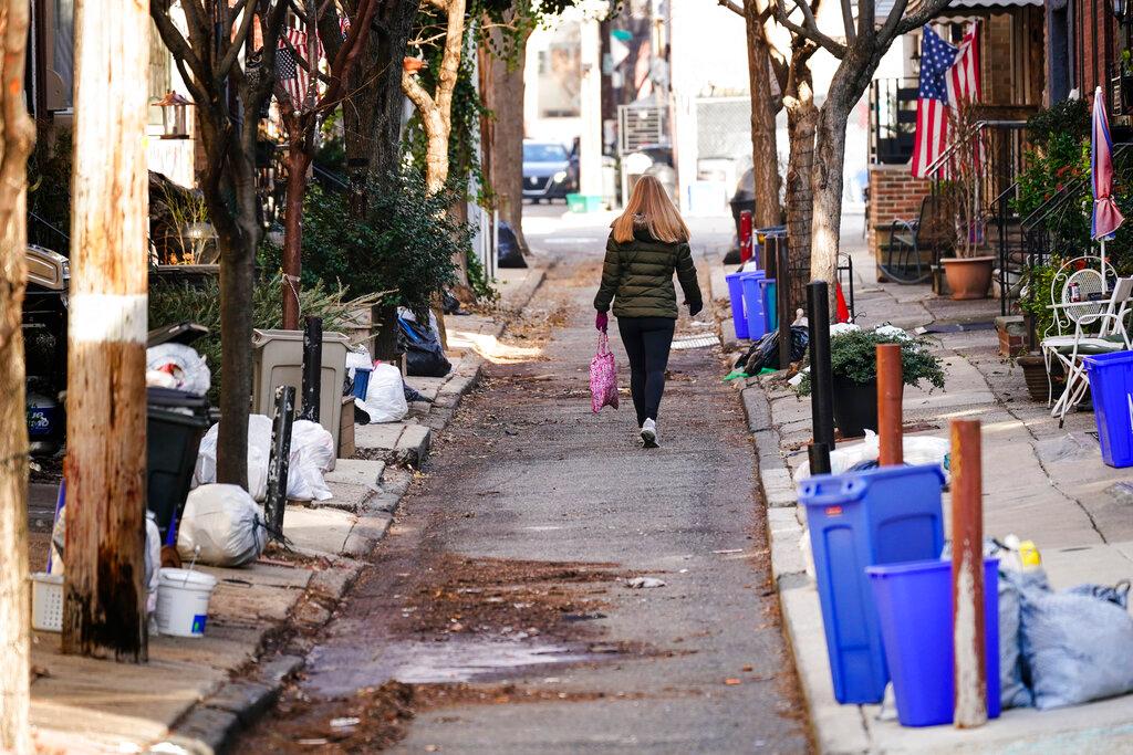 A woman walks past trash that is sitting out for collection in Philadelphia