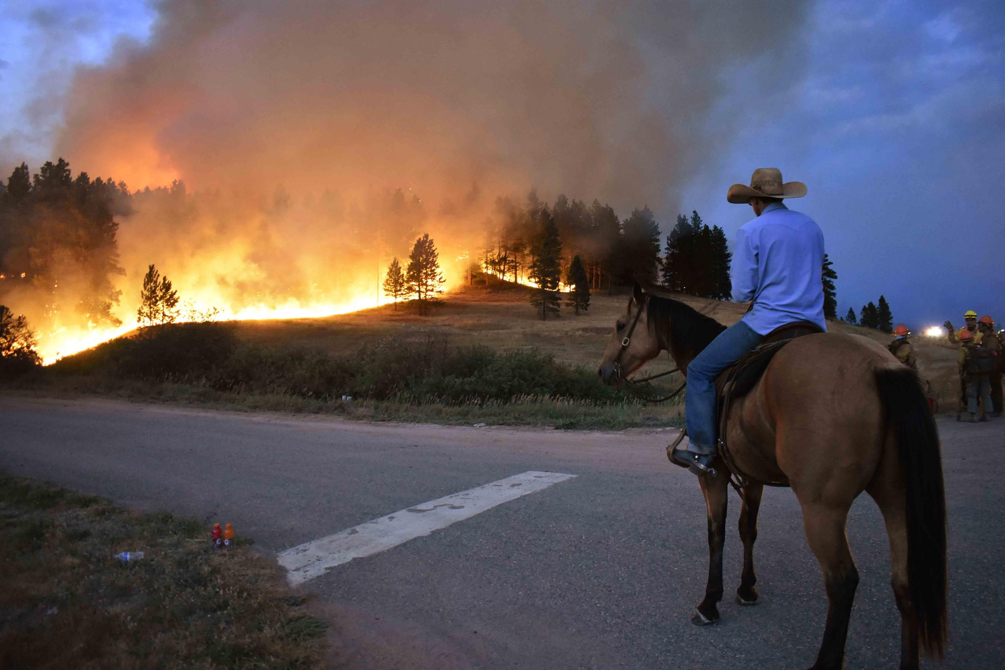 Rowdy Alexander watches from atop his horse as a hillside burns on the Northern Cheyenne Indian Reservation on Aug 11, 2021, near Lame Deer, Mont