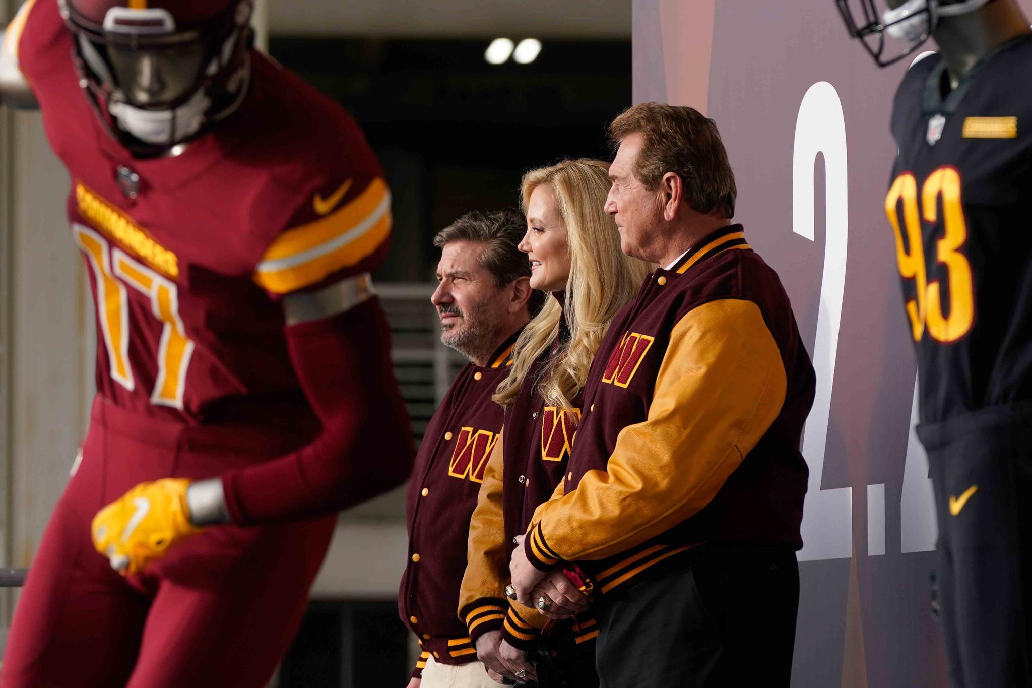 Dan, left, and Tanya Snyder, co-owner and co-CEOs of the Washington Commanders, stand with former quarterback Joe Theismann, right, after unveiling their NFL football team's new identity, Wednesday, Feb. 2, 2022, in Landover, Md.