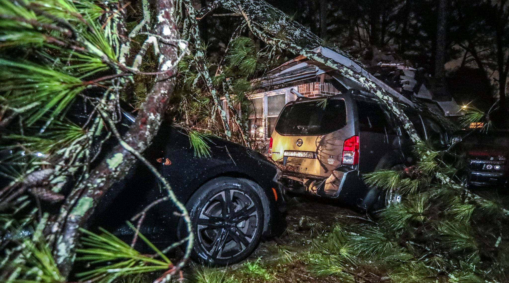 Fallen tree branches cover a yard and vehicles