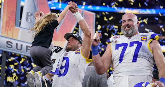 Two football players after Super Bowl win. One is pulling his 3-year-old daughter up in the air.
