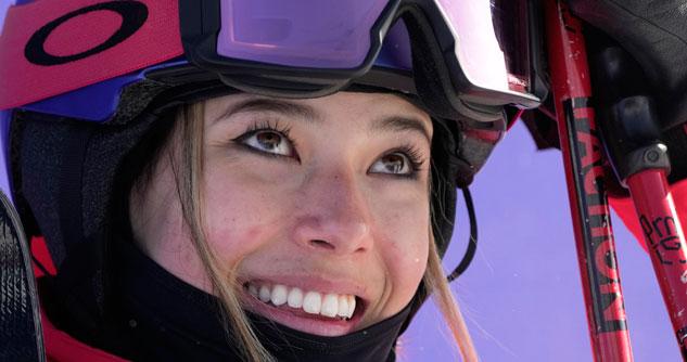 Close-up face of young woman with ski poles and goggles