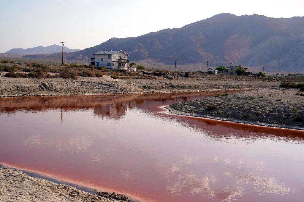 Clouds and nearby mountains are reflected in a polluted canal, once used as a boating dock, along the Salton Sea in Desert Shores, Calif.