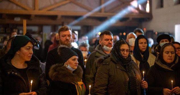 People holding candles next to Ukrainian soldier's body