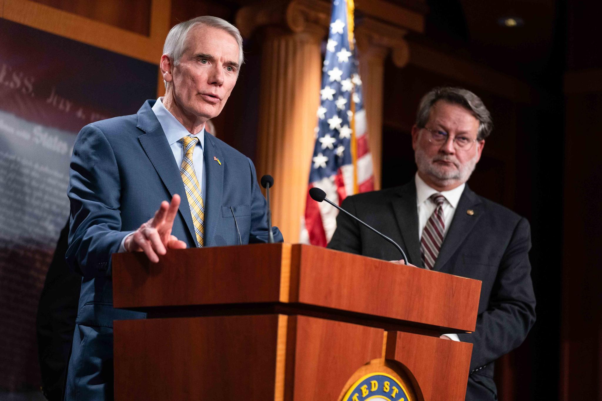 Sen. Gary Peters, D-Mich., right, listens as Sen. Rob Portman, R-Ohio, speaks during a news conference after the Senate passed a bill to shore up the U.S. Postal Service, on Capitol Hill, Tuesday, March 8, 2022, in Washington.