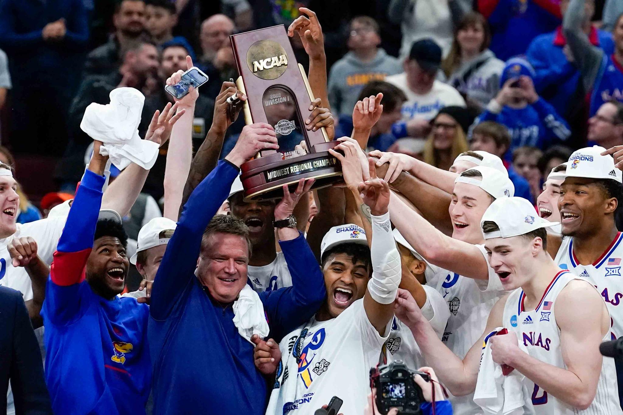 Kansas head coach Bill Self and players hold up the winning trophy after a college basketball game in the Elite 8 round of the NCAA tournament against Miami Sunday, March 27, 2022, in Chicago. Kansas won 76-50 to advance to the Final Four.