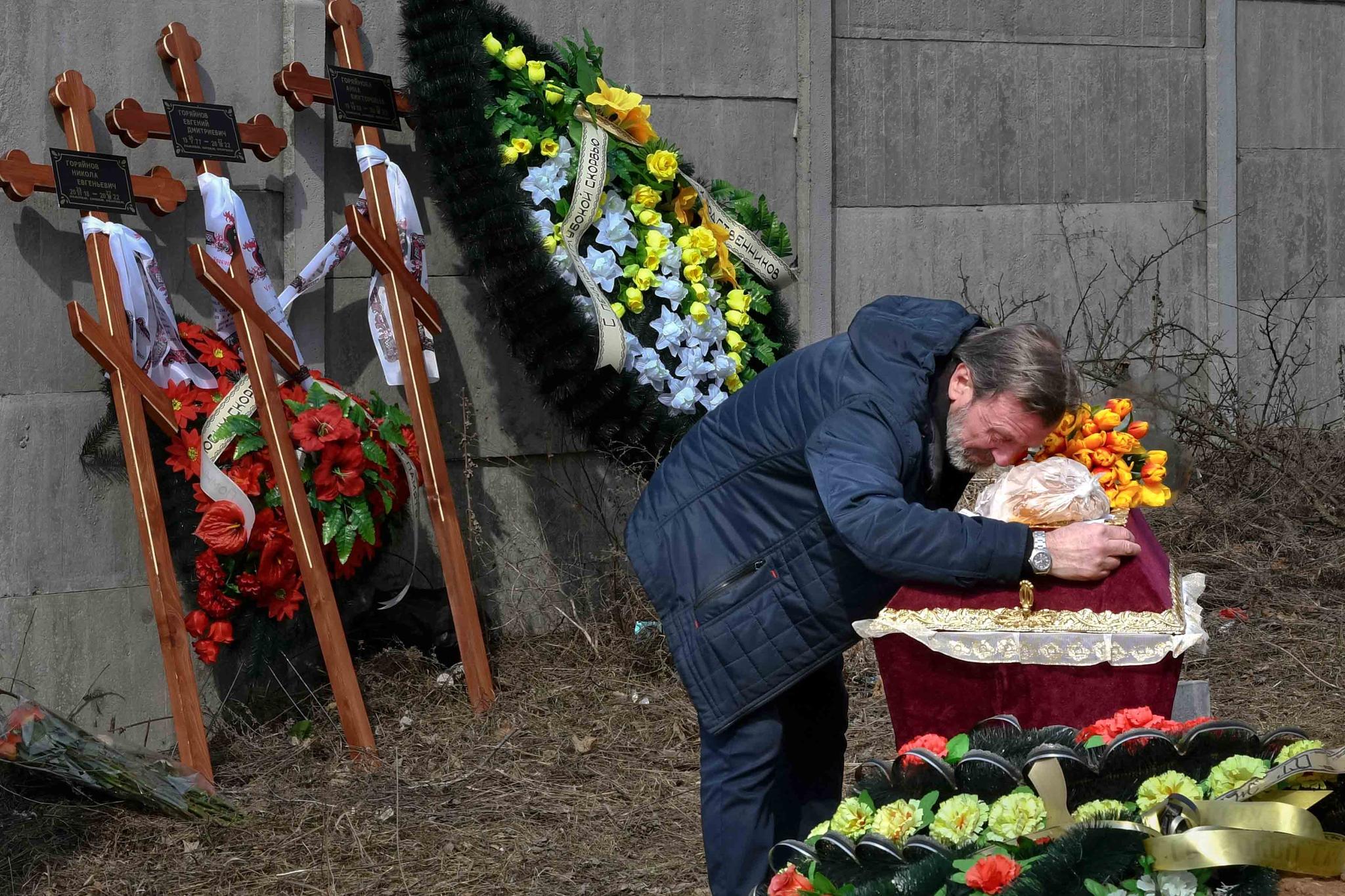 A relative mourns on the coffin with the body of 3 year-old Mykola Goryainiv, who died with his parents as they were driving a car trying to evacuate from a fighting zone in Kharkiv region, during a funeral ceremony in Kramatorsk, Ukraine, Wednesday, March 30, 2022.