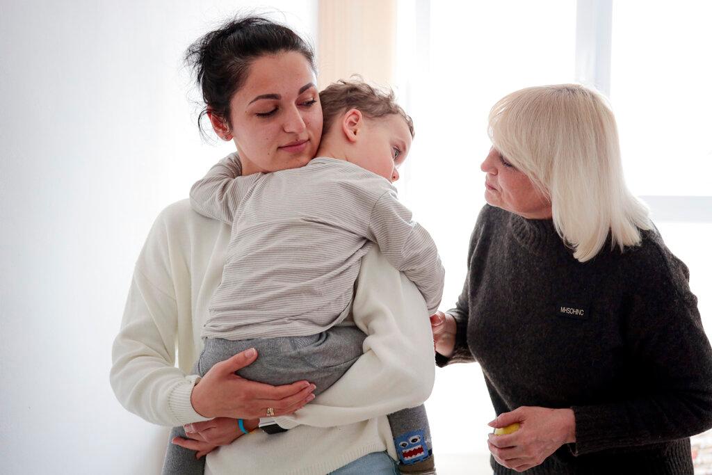 Refugee Karina Buiukli holds her 2-year-old son, Maxim as her mother stands aside