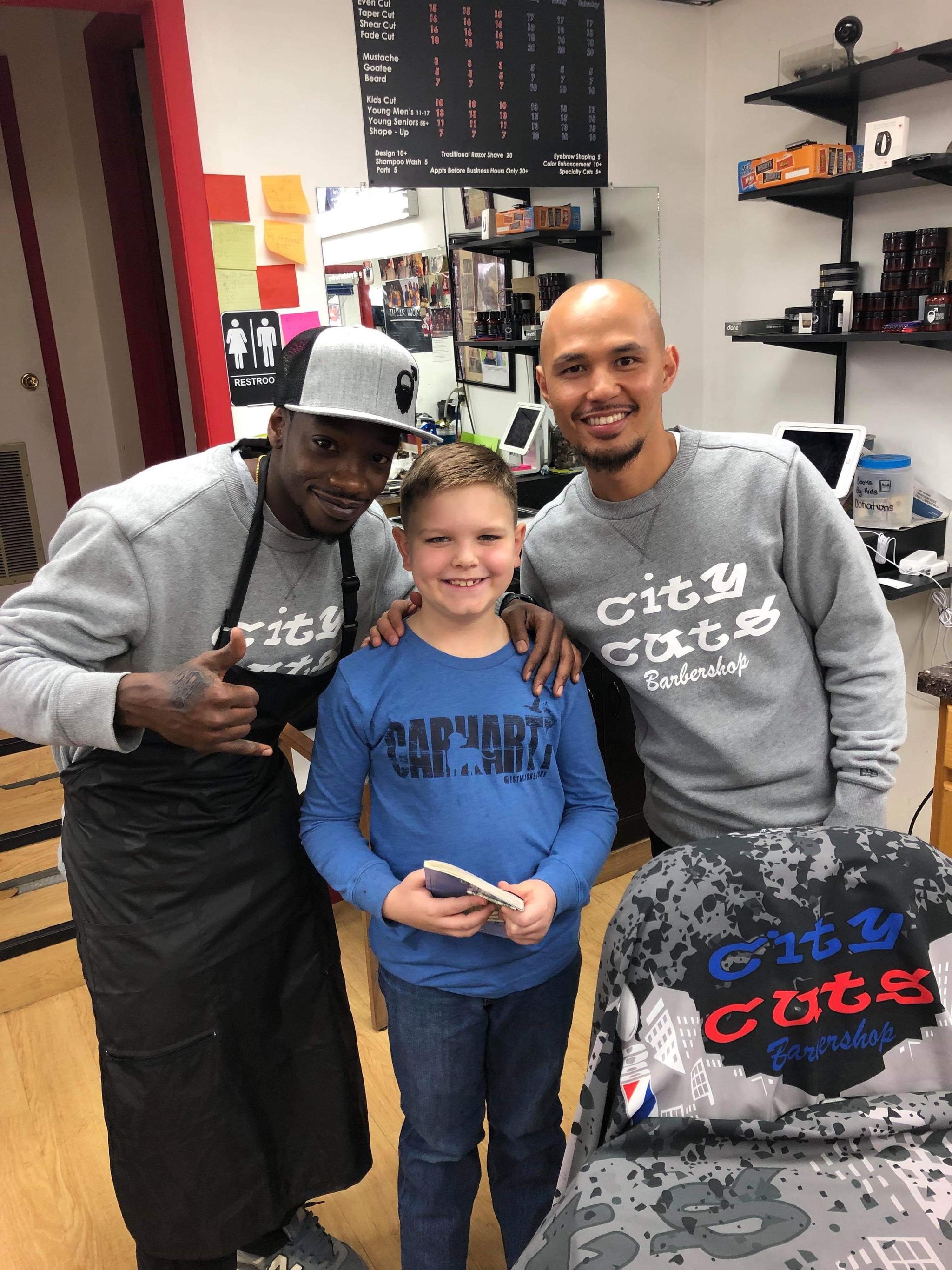 Boy and barbers at City Cuts Barbershop
