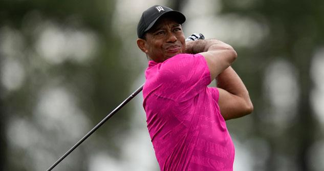 Tiger Woods in hot pink shirt and black ball cap, swinging a golf club