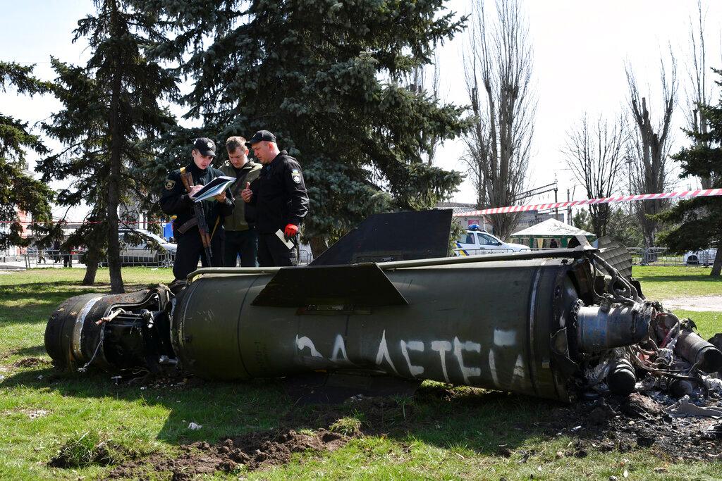Ukrainian servicemen stand next to a fragment of a Tochka-U missile with a writing in Russian "For children" , on a grass after Russian shelling at the railway station in Kramatorsk, Ukraine,