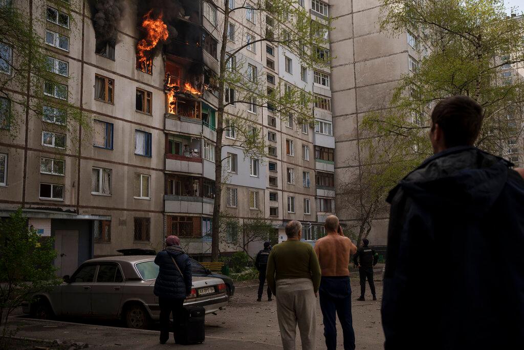 People watch as a residential building burns following a Russian bombardment in Kharkiv, Ukraine
