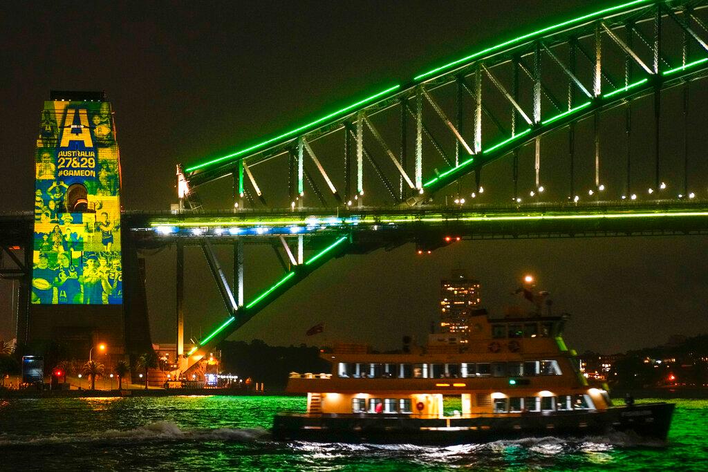 A Sydney ferry sails past the illuminated pylon of the Sydney Harbour Bridge