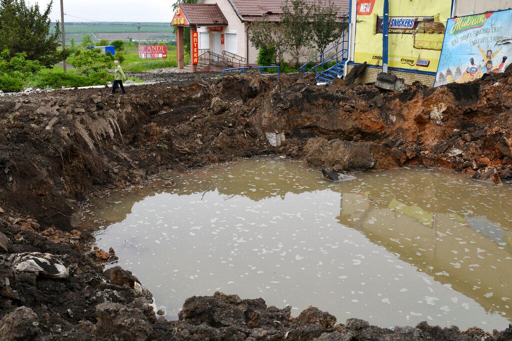 A woman walks past a crater of an explosion after Russian shelling in Soledar, Donetsk region, Ukraine